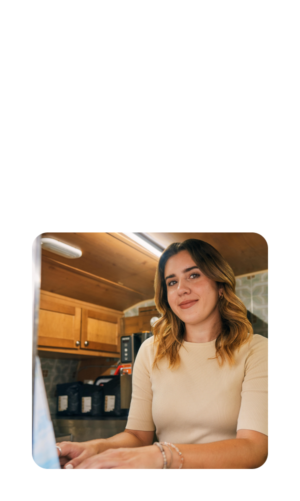 TurboTax customer Carina is smiling as she looks up from her laptop on the table.