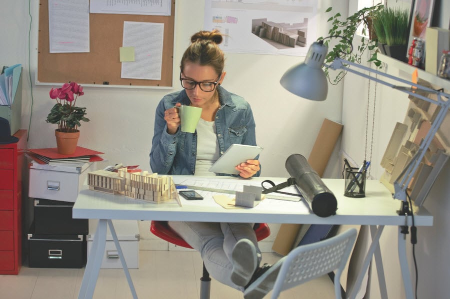 Woman with a coffee cup in hand at a desk with lots of papers